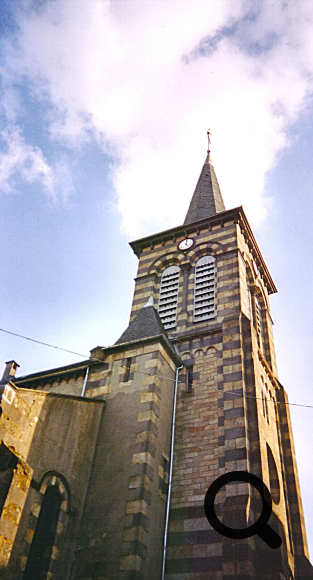 Clocher de l'église en pierre avec un ciel partiellement nuageux en arrière-plan.