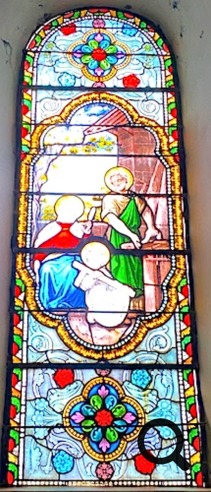 Vitrail coloré représentant trois figures humaines, dont une en vert, entourées de motifs floraux et géométriques.