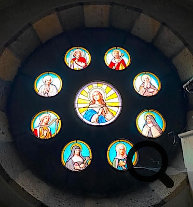Vitrail circulaire avec neuf médaillons représentant des figures religieuses entourant une figure centrale.