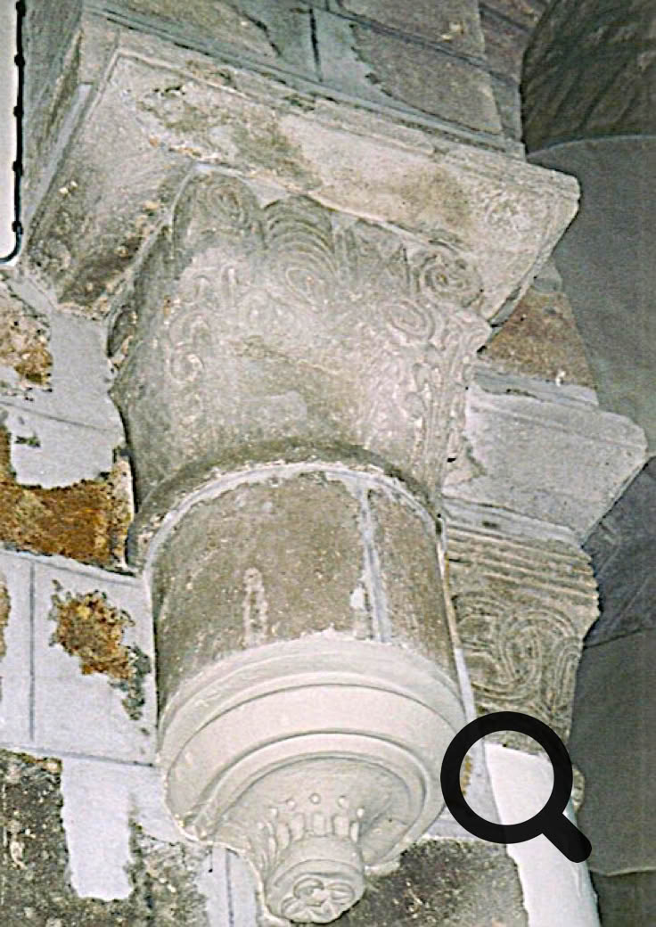 Chapiteau en pierre sculptée avec des motifs décoratifs, fixé à un mur en pierre.