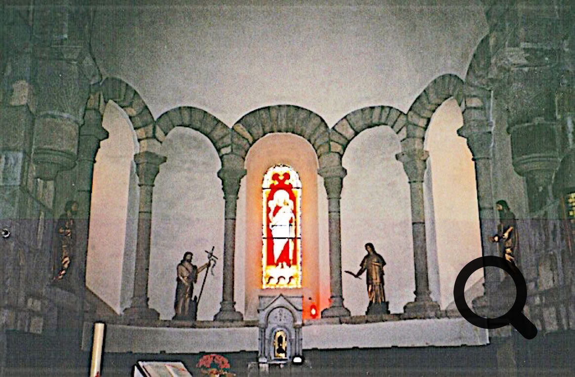Intérieur de l'église avec des arches en pierre, un vitrail coloré au centre, et plusieurs statues sur un autel.