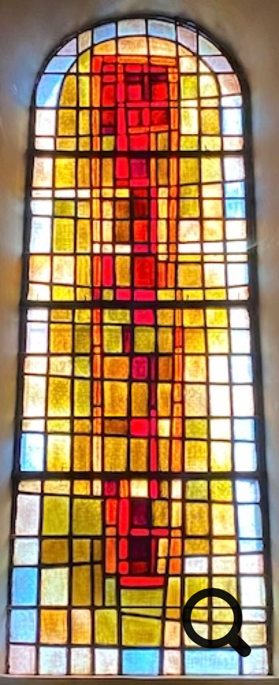 Vitrail coloré avec des motifs géométriques rouges, jaunes et bleus.