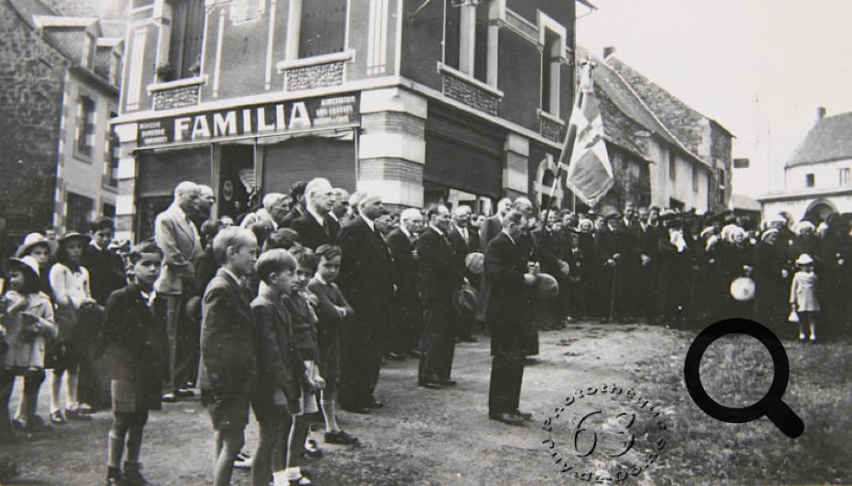 Une foule de personnes rassemblées devant un bâtiment avec l'inscription "FAMILIA", certaines portant des drapeaux.