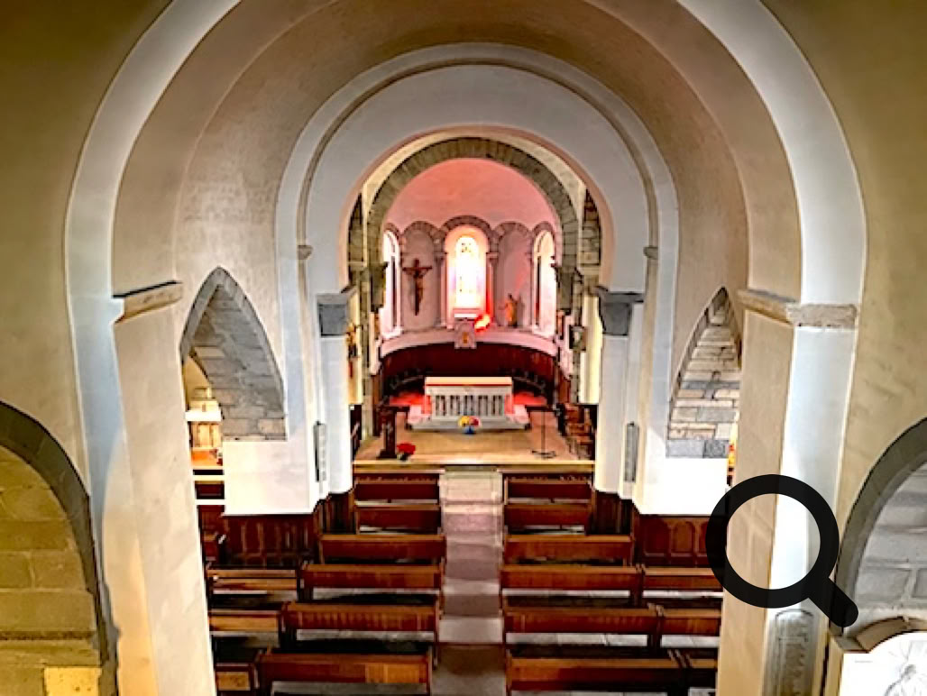 Intérieur de l'église avec des bancs en bois, un autel éclairé et des arches en pierre.