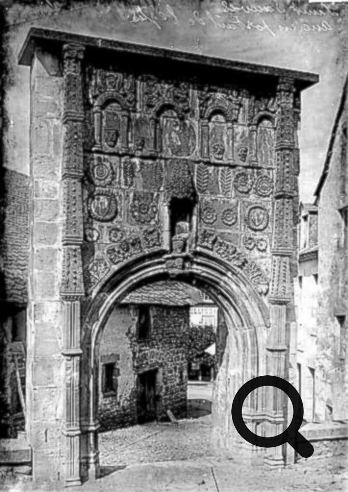 Arc en pierre orné de motifs, avec une rue pavée visible à travers l'ouverture.