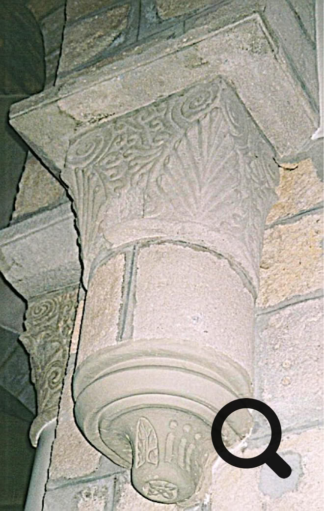 Chapiteau en pierre sculptée avec des motifs décoratifs, fixé à un mur en pierre.