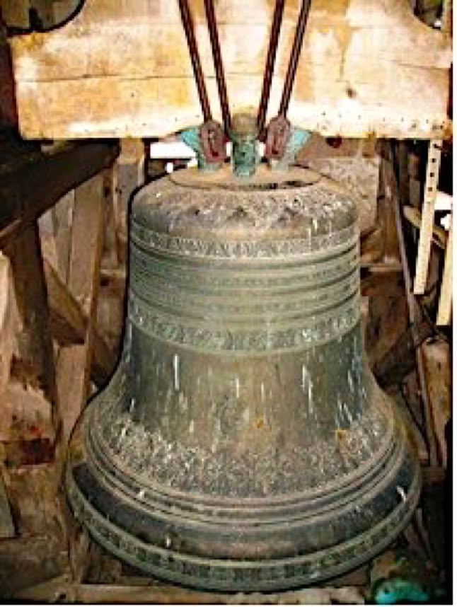 Une grande cloche en métal suspendue dans une structure en bois.