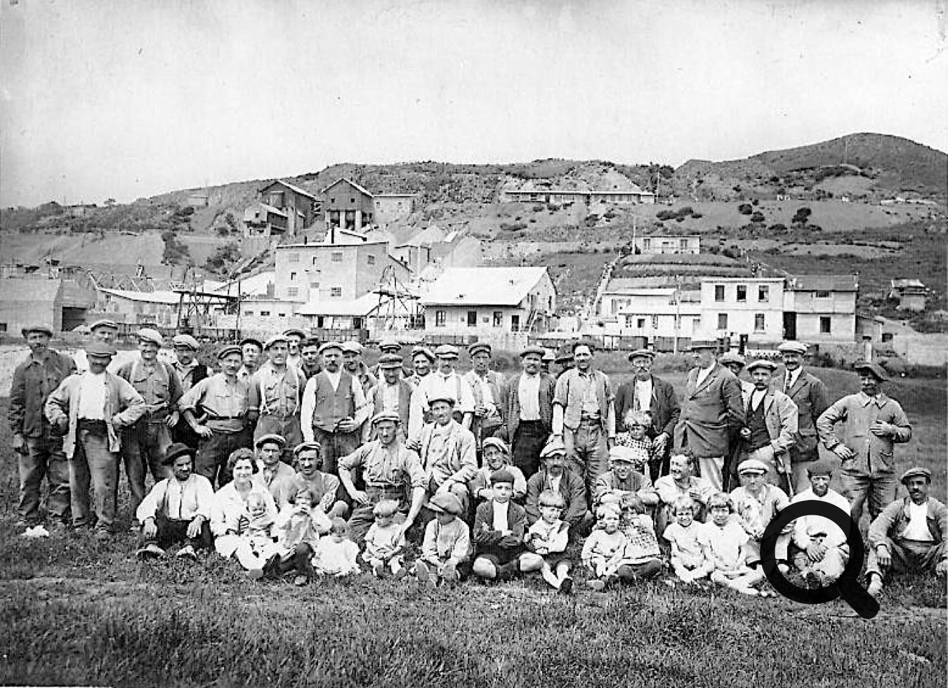 Un groupe de personnes posant devant des bâtiments avec des collines en arrière-plan.
