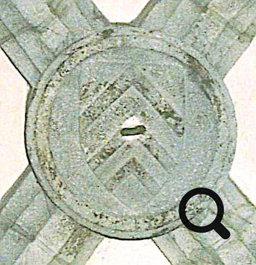 Motif circulaire en pierre avec des chevrons gravés, situé à l'intersection de nervures croisées.
