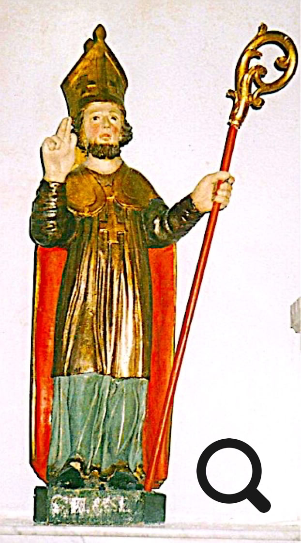 Statue en bois d'une figure religieuse avec une mitre, tenant une crosse et levant la main droite, vêtue d'une robe et d'une cape rouge.