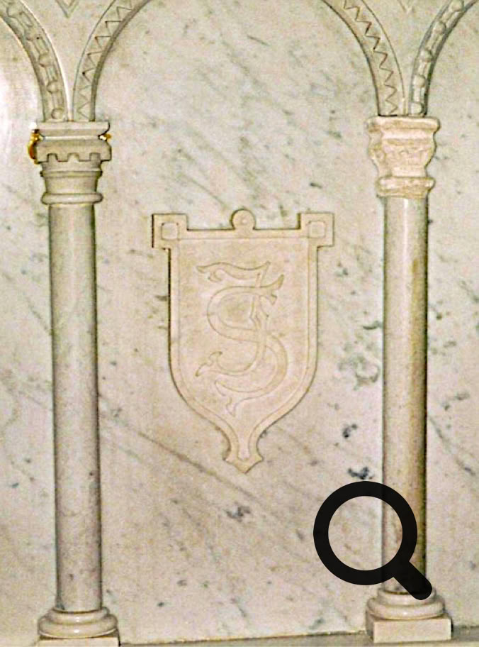 Deux colonnes en marbre avec des arcs décoratifs, et un blason sculpté au centre du mur.