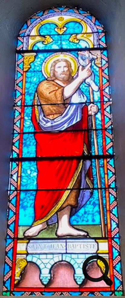 Vitrail représentant une figure religieuse avec une auréole, vêtue de rouge et de blanc, tenant un bâton, sur un fond bleu.